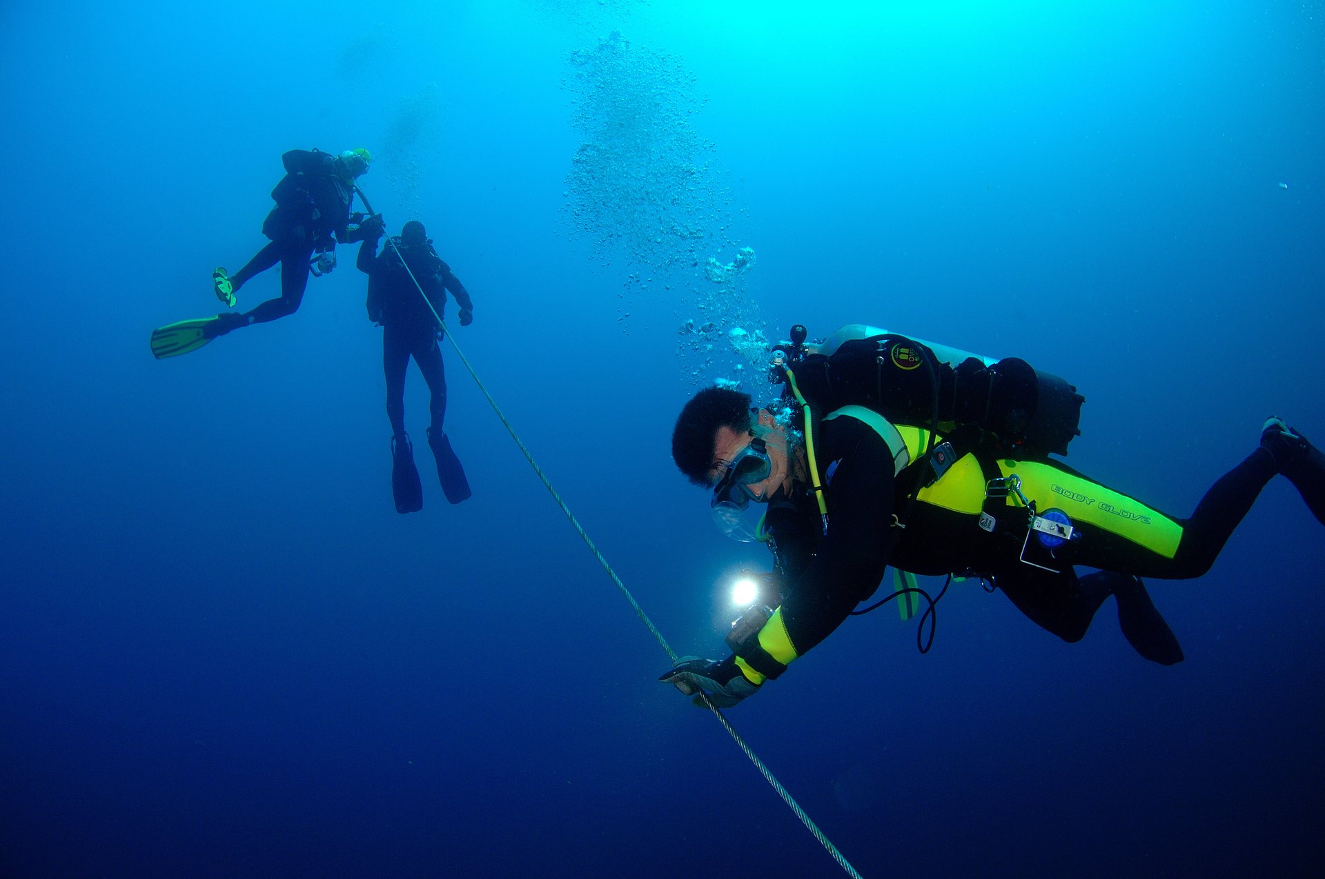Scuba divers descending beneath a dive boat into deep blue water